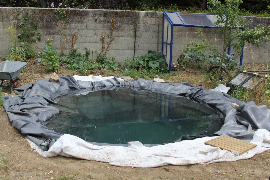 On pose la bâche EPDM du bassin de jardin extérieur