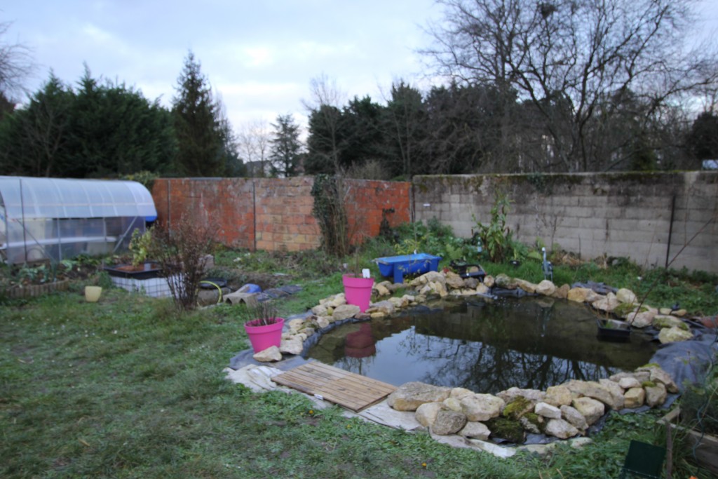 On pose des pierres autour du bassin pour maintenir la bâche EPDM